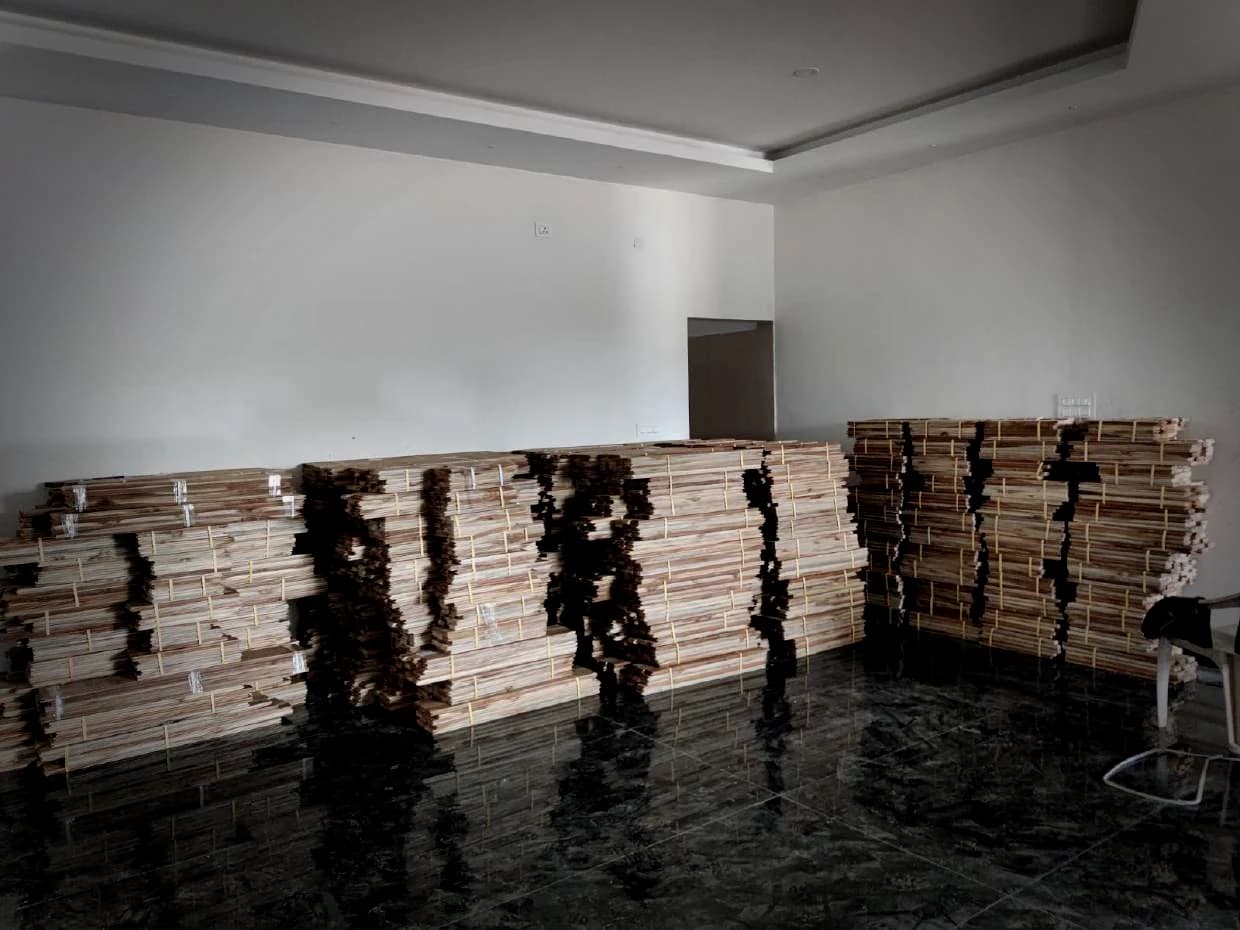 Bundles of sawn teak stacked in a finished room, waiting to be laid